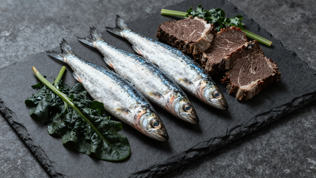Sardines, beef and leafy greens on a dark slate board